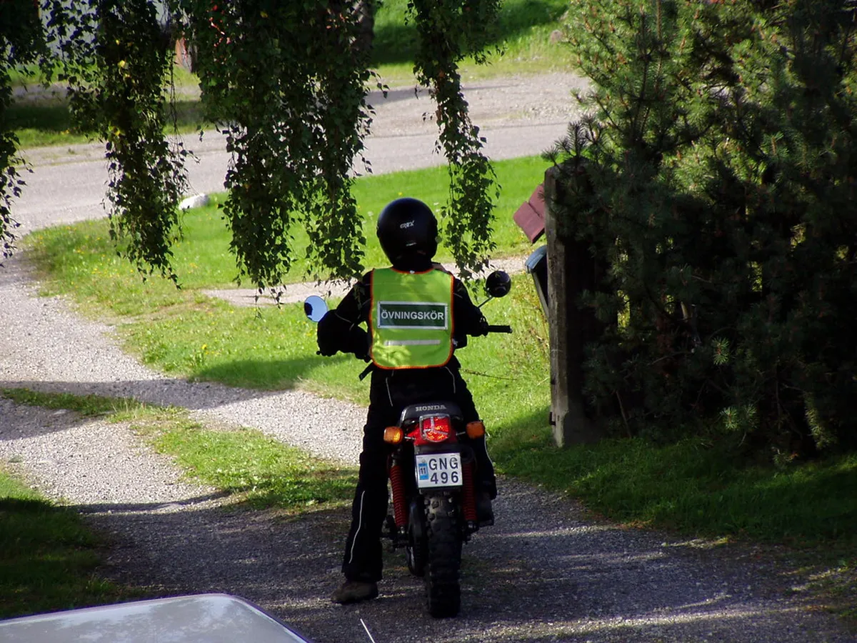 Alumno con chaleco de prácticas en una moto pequeña por un camino